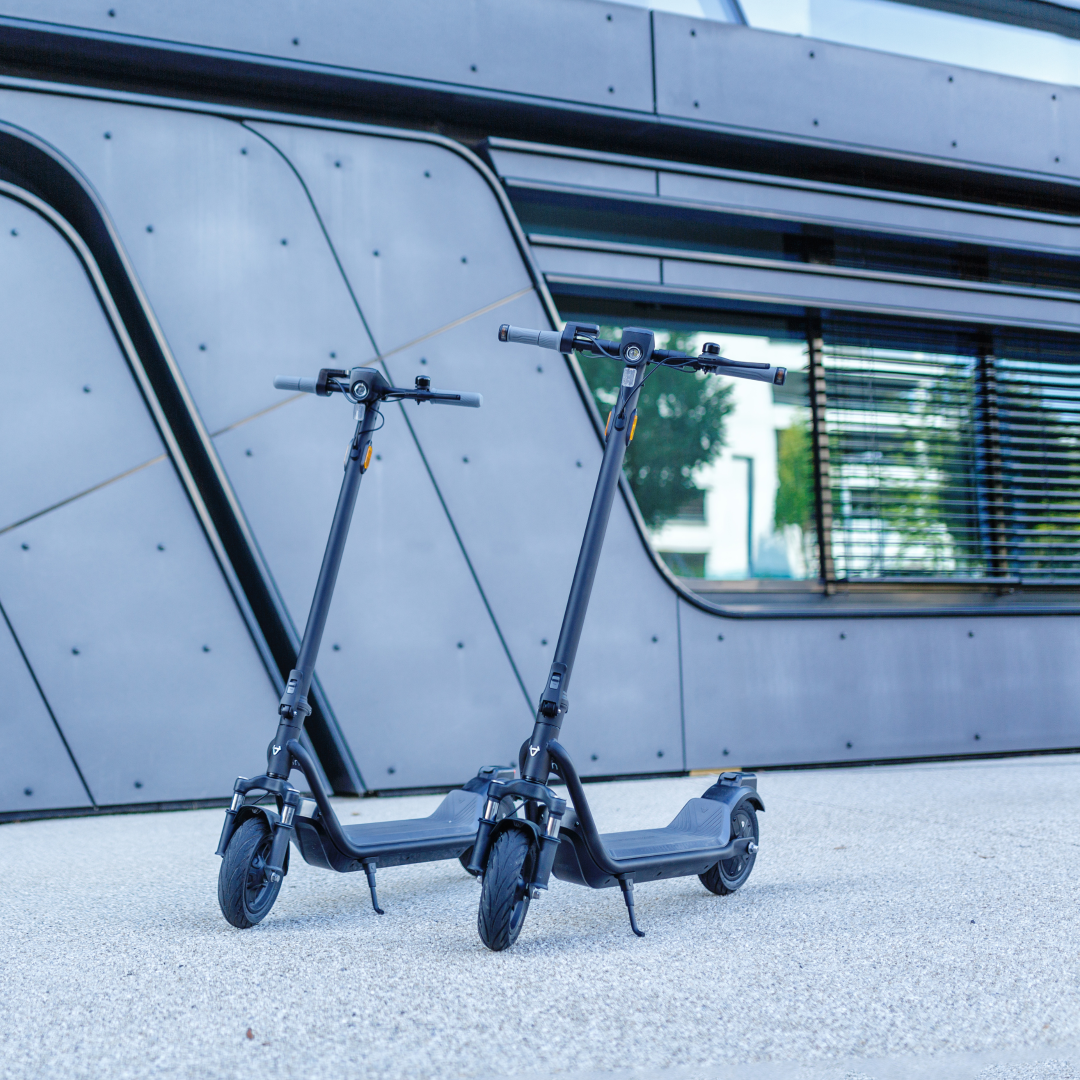 Two NIU - KQi100F Electric KickScooters in a lifestyle photo on the street